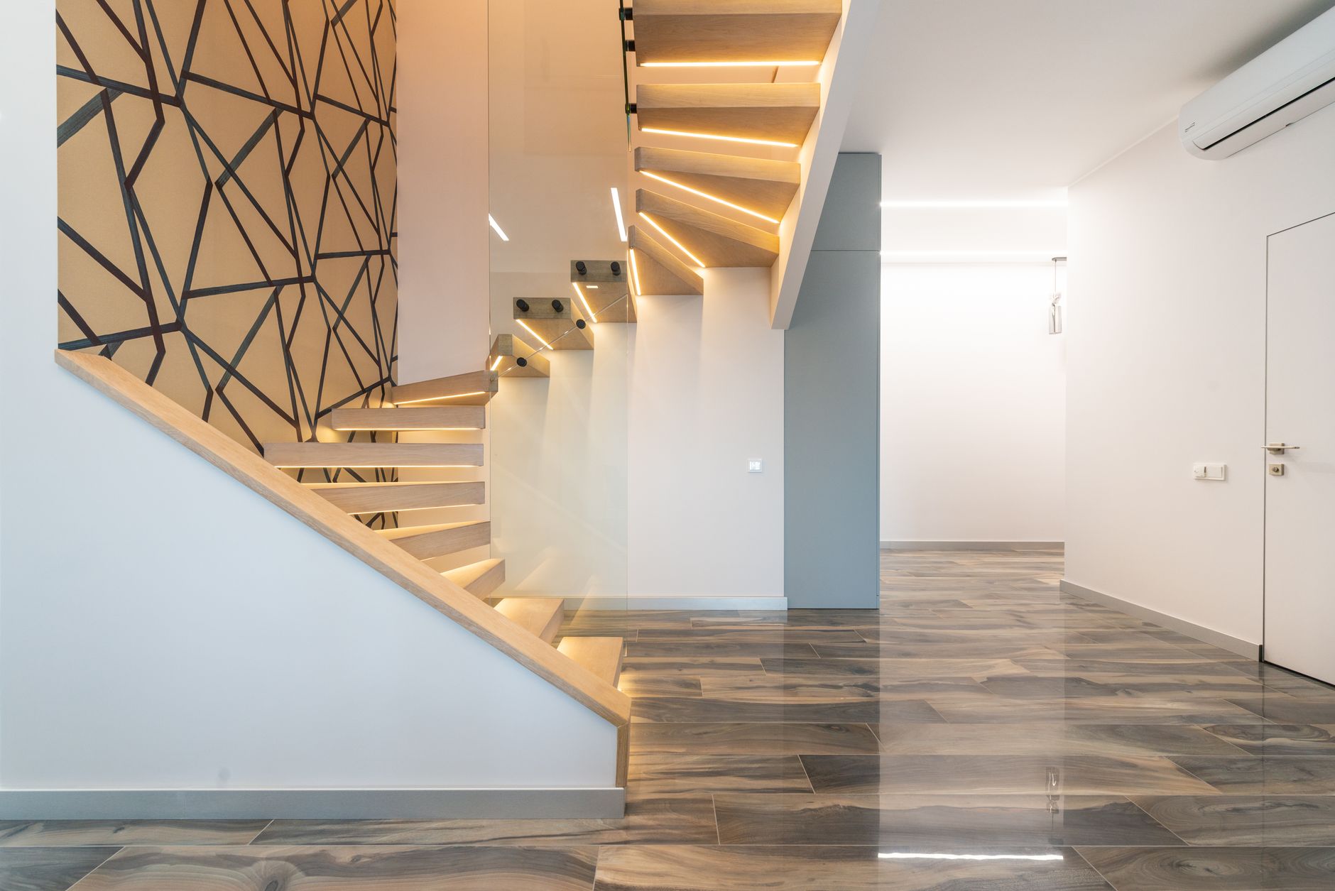 Escalier intérieur en bois avec garde-corps vitré dans un hall clair